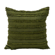 The Funda de Cojín Bogotá by Intima Hogar is a square, dark green cushion cover with horizontal textured fringe and slightly pointed corners, offering a soft fabric look for decorative layering. Shown against a white background.