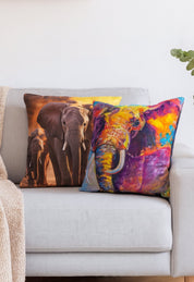 Dos cojines de Intima Hogar adornan el sofá: uno es el "Cojín Elefante" con elefantes al atardecer y el otro luce un diseño colorido. Se aprecia además una manta beige y una planta verde.