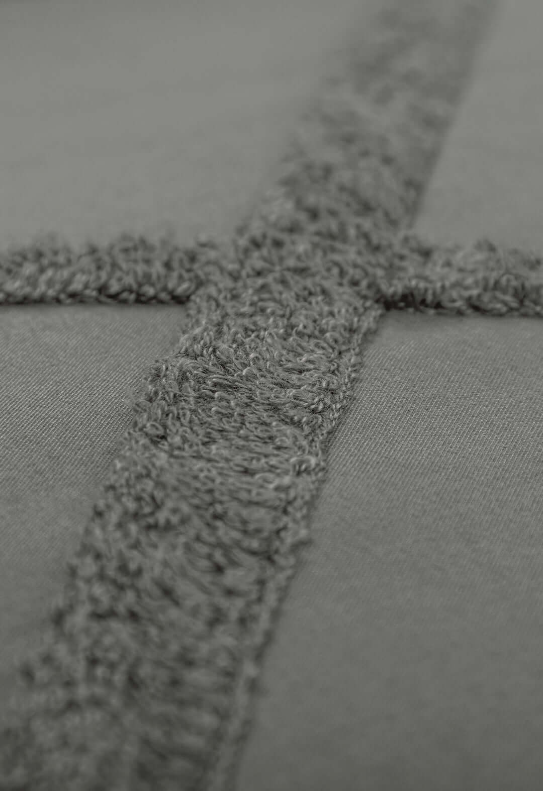 Close-up of the Juego de Edreduvet Bordado Hamburgo by Intima Hogar, featuring soft gray fabric with a raised cross pattern—ideal for a minimalista juego de cama.