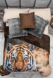 A neatly made bed features Intima Hogar's Cobertor Digital Ultra Suave Bengala with a tiger face design, beige sheets, gray furry pillows, a brown pillow, and tonos tierra palette, viewed from above with marble floor and nightstands.