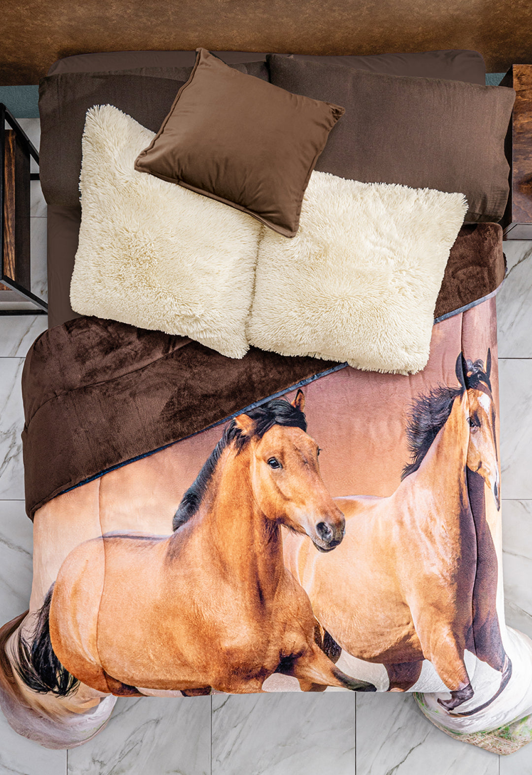A neatly made bed with brown pillows, white cushions, and the Cobertor Digital Ultra Suave Caballos by Intima Hogar, featuring a realistic print of two running horses. The crisp white tile floor adds a striking contrast.