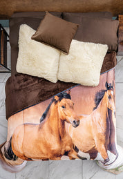 A neatly made bed with brown pillows, white cushions, and the Cobertor Digital Ultra Suave Caballos by Intima Hogar, featuring a realistic print of two running horses. The crisp white tile floor adds a striking contrast.