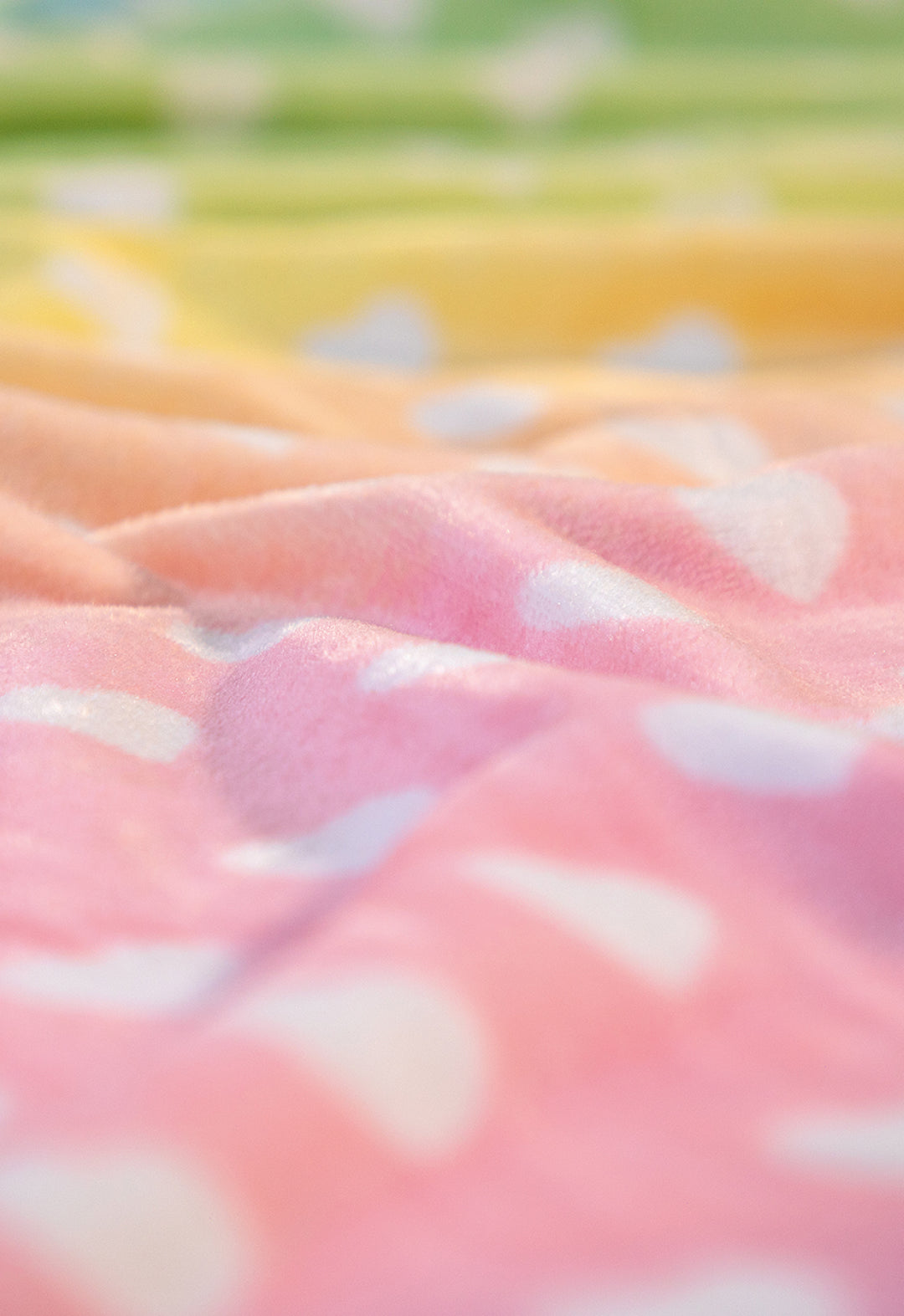 Close-up of the Cobertor Flannel Ligero Azúcar by Intima Hogar, featuring pastel rainbow hues with white polka dots, soft gentle folds, and a smooth flannel texture.