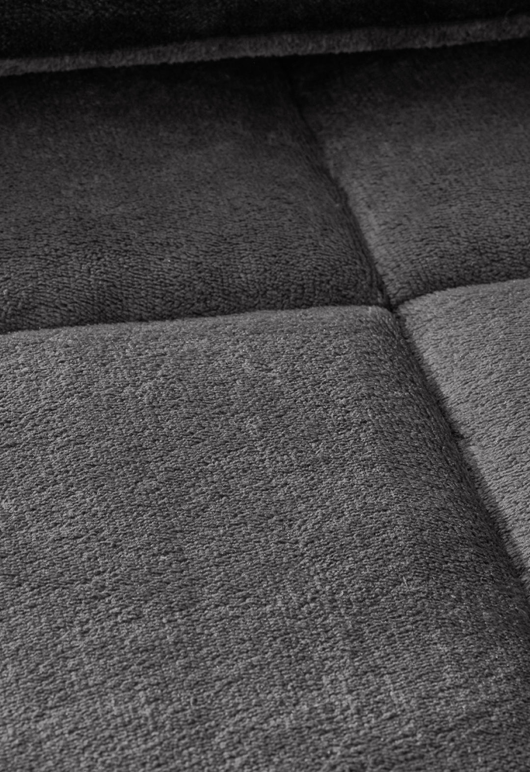 Close-up of the Intima Hogar Cobertor Flannel Extra Suave Estambul in dark gray, showing its textured surface and large stitched squares for calidez duradera and abrigo ligero.