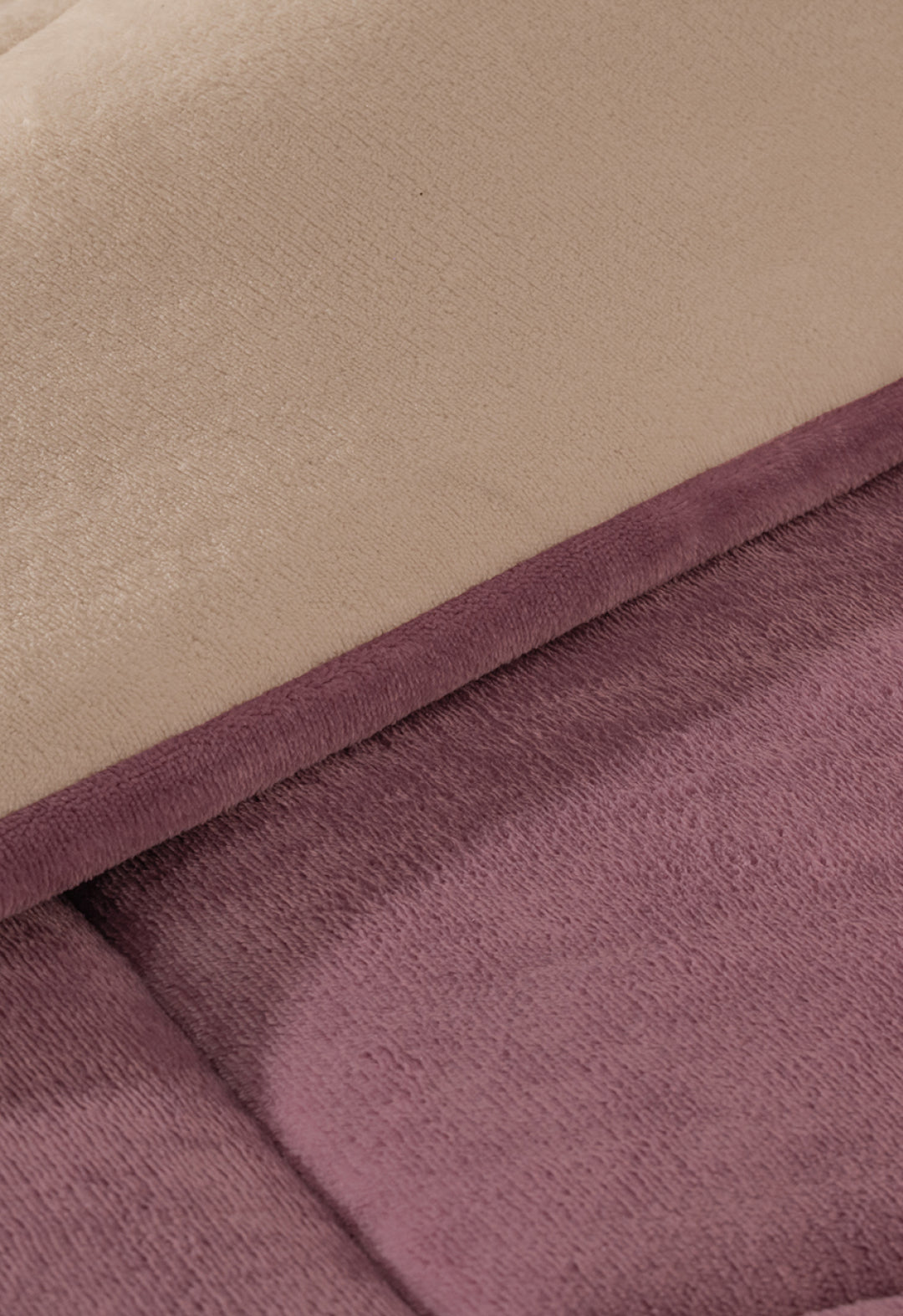 Close-up of two overlapping Intima Hogar Cobertor Flannel Extra Suave Italia blankets, one beige and one mauve, showcasing their ultra-soft, plush textured surfaces.