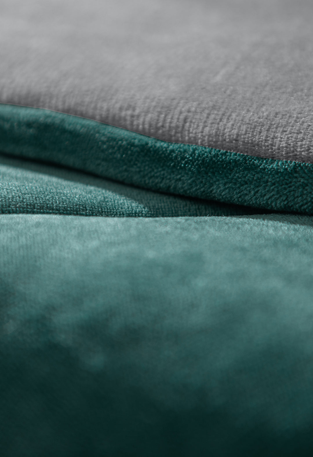 Close-up of two soft, textured fabric surfaces—light gray above and teal below—showcasing the Cobertor Flannel Extra Suave Mediterráneo by Intima Hogar with its smooth, velvety look and elegante diseño doble vista.