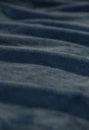 Close-up of the Cobertor Flannel Ligero Ontario Azul Marino by Intima Hogar, featuring gentle, wavy folds and a textured, soft surface highlighted by the lighting for added depth and smoothness.