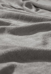 Close-up of the Cobertor Flannel Ligero Ontario Gris by Intima Hogar, featuring soft, textured gray fabric with gentle folds and light shadows for a cozy and comfortable look.