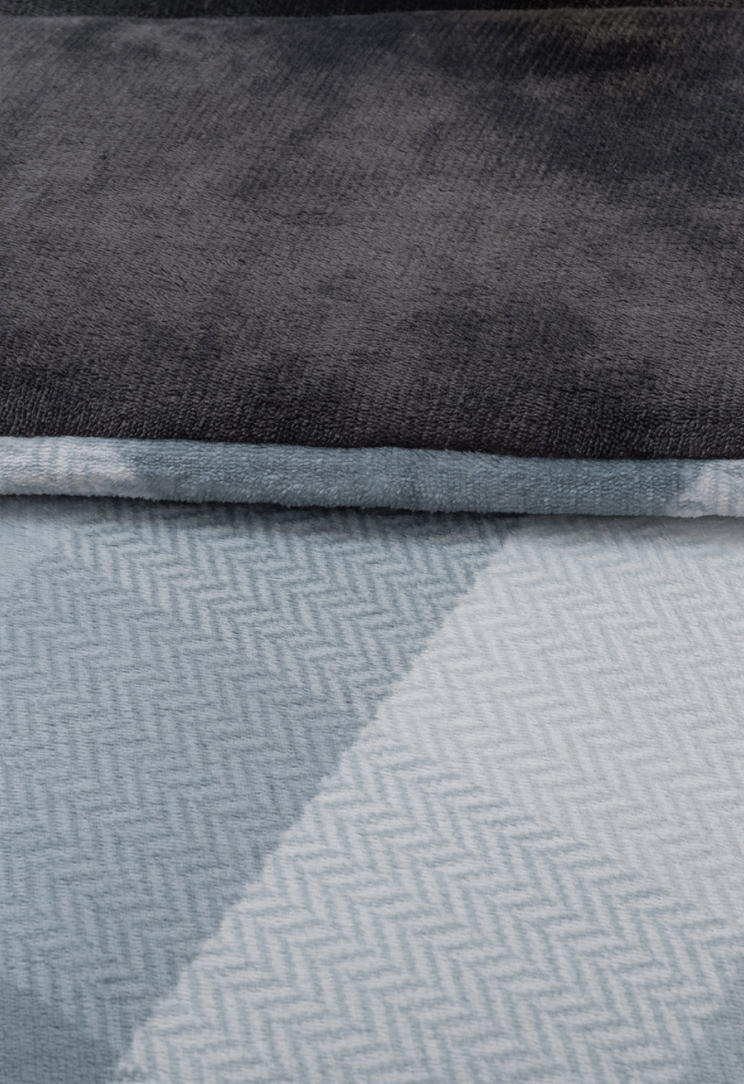 A close-up of two folded blankets: on top, the Cobertor Flannel Extra Suave Palacio by Intima Hogar in solid dark gray, and beneath, a light blue and white geometric pattern—ideal as a cozy cobertor para invierno.