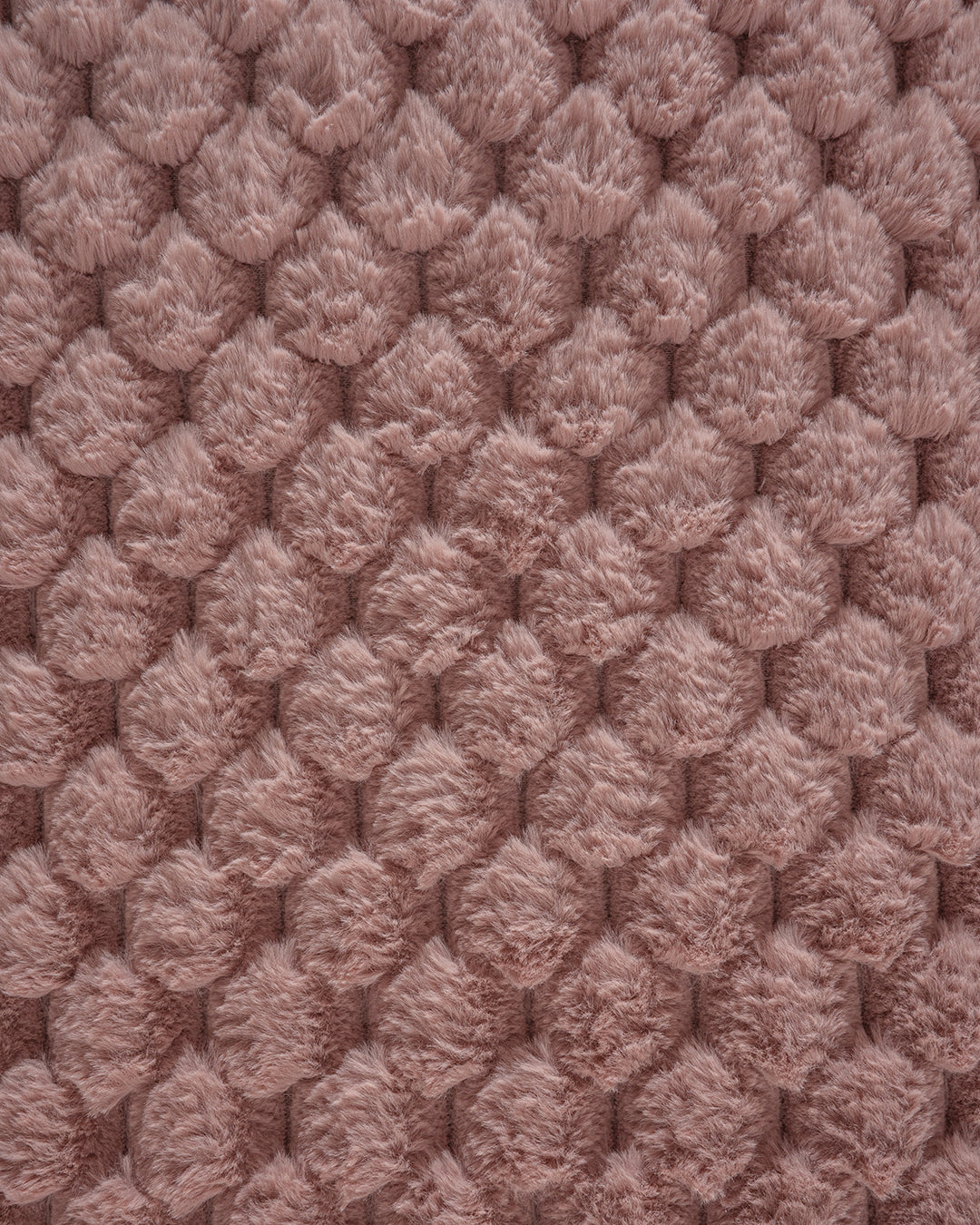 Close-up of the Frazada de Lujo Aruba by Intima Hogar: palo rosa textured pink fabric with a raised circular pattern and soft, fluffy finish—perfect for adding textura ligera to any habitación.