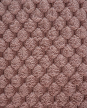 Close-up of the Frazada de Lujo Aruba by Intima Hogar: palo rosa textured pink fabric with a raised circular pattern and soft, fluffy finish—perfect for adding textura ligera to any habitación.