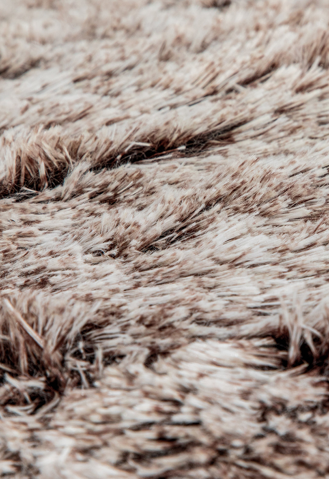 Close-up of the soft, fluffy texture of the Intima Hogar Cobertor Platinum Extra Suave Glacial, featuring beige and brown tones with varied strands for a cozy, inviting look.