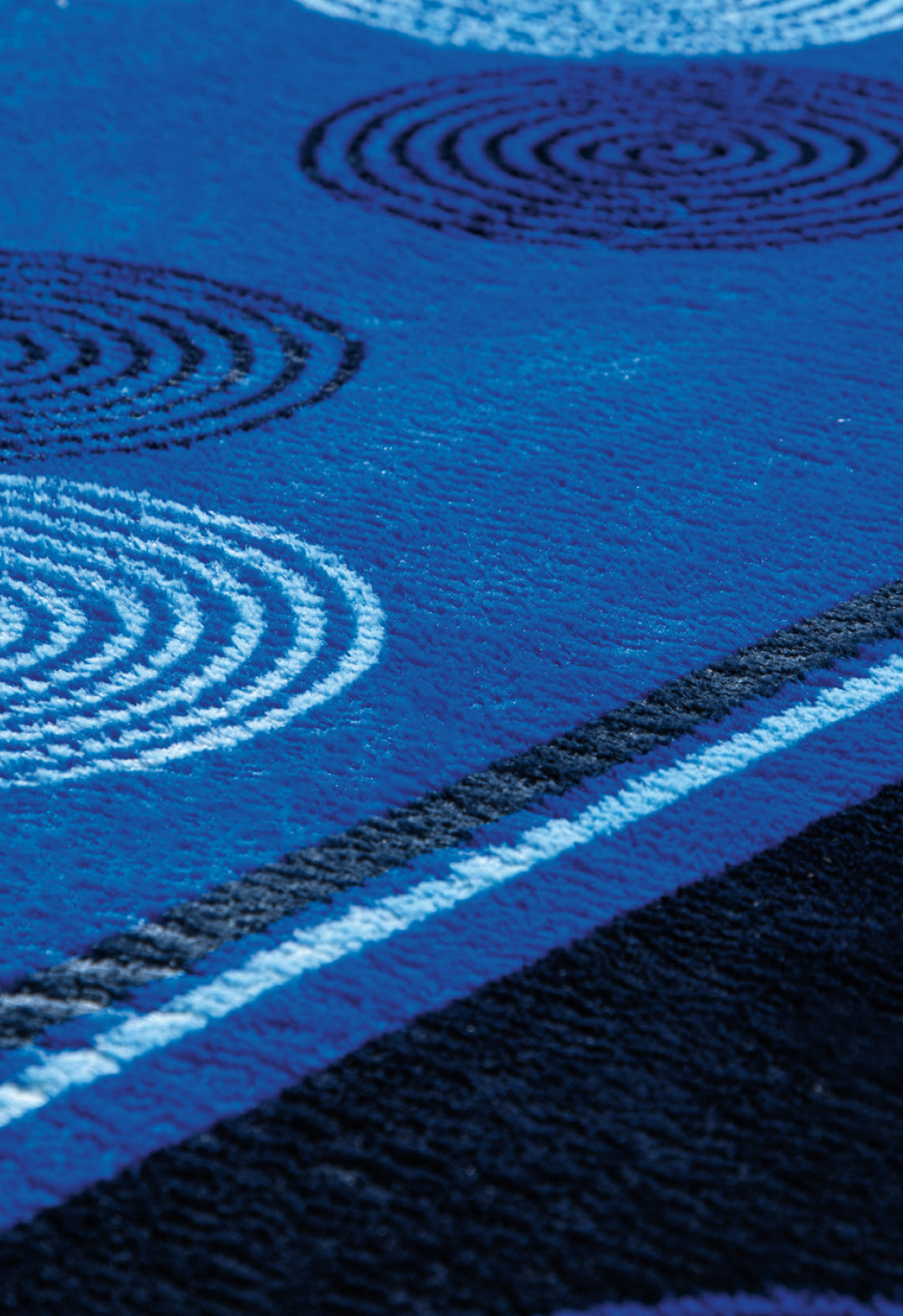 A close-up of the Cobertor Flannel Extra Suave Sfera by Intima Hogar shows its blue textured design with white and black circular patterns and wavy lines—ideal for modern bedrooms.