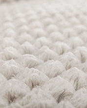 Close-up of the Cojín Nickel by Intima Hogar: its soft, fluffy white texture and quilted pattern create a cozy, plush look, evoking comfort and warmth—perfect for un elegante diseño de cojín.