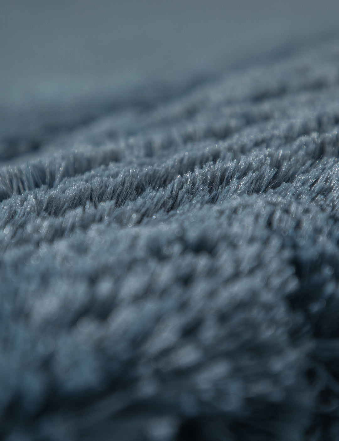 Close-up of the soft, blue-gray Frazada de Lujo Bruselas by Intima Hogar, showing plush textured fibers in sharp detail against a softly blurred background for a luxurious, cozy look.