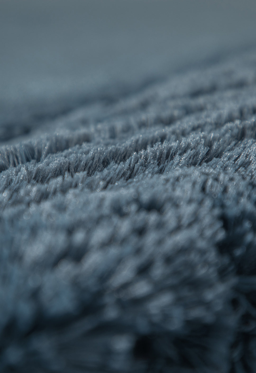 Close-up of the soft, blue-gray Frazada de Lujo Bruselas by Intima Hogar, showing plush textured fibers in sharp detail against a softly blurred background for a luxurious, cozy look.
