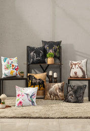 A cozy living room with cojines decorativos, including Intima Hogar's Cojín Estampado Caballo, plus animal and floral designs, all arranged on shelves and a beige rug against a textured wall.