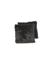 Dos cojines negros, cuadrados y afelpados del Juego de Cojines Albania de Intima Hogar se muestran sobre fondo blanco, uno ligeramente delante del otro.