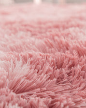 Close-up of a soft, fluffy pink shag rug with long fibers. Its cozy texture and plush thickness make it the perfect spot for lounging or pairing with the Cojín de Lujo Flamenco Ball by Intima Hogar for extra comfort and style.