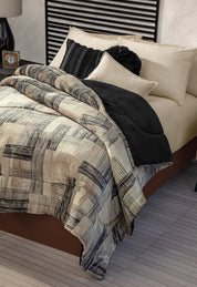 A neatly made bed with Intima Hogar's Coordinado de Cobertor Digital Soft Big Ben, beige sheets, black and cream decorative pillows. The room includes a striped headboard and a bedside table with a clock.