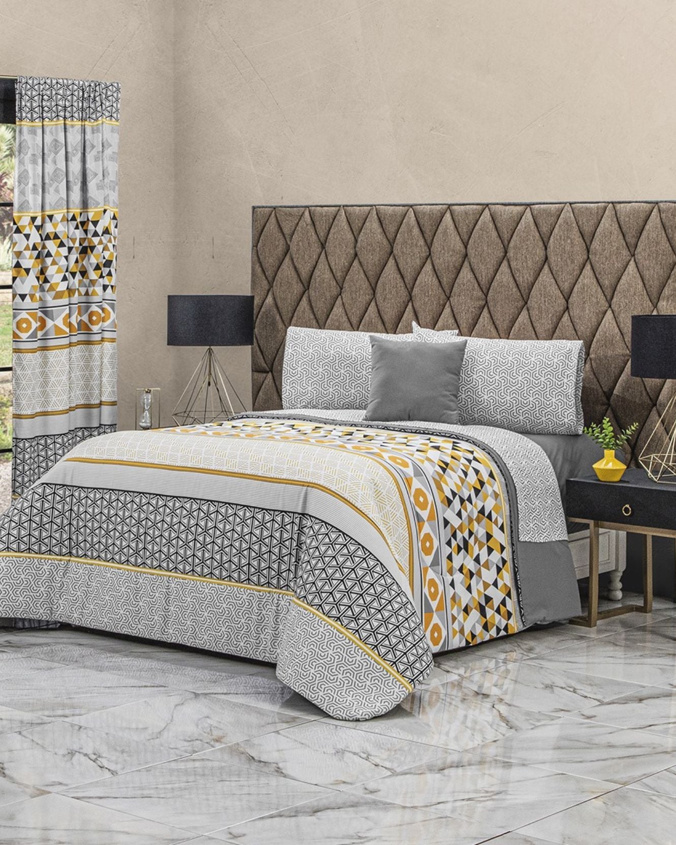A modern bedroom features the Coordinado de Edredón Super Suave Leo by Intima Hogar with a geometric design in gray, white, yellow, and black. The space has marble floors, matching curtains, a tufted headboard, and two black lamps on nightstands.