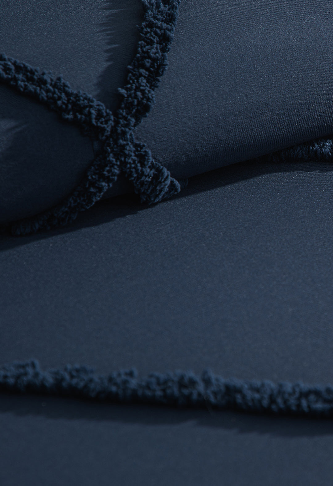 Close-up of the Coordinado de Edredón Luxury Seúl by Intima Hogar, featuring dark blue textured fabric with crisscrossed lines and a fuzzy trim, perfect for adding cozy comfort to your bedding.