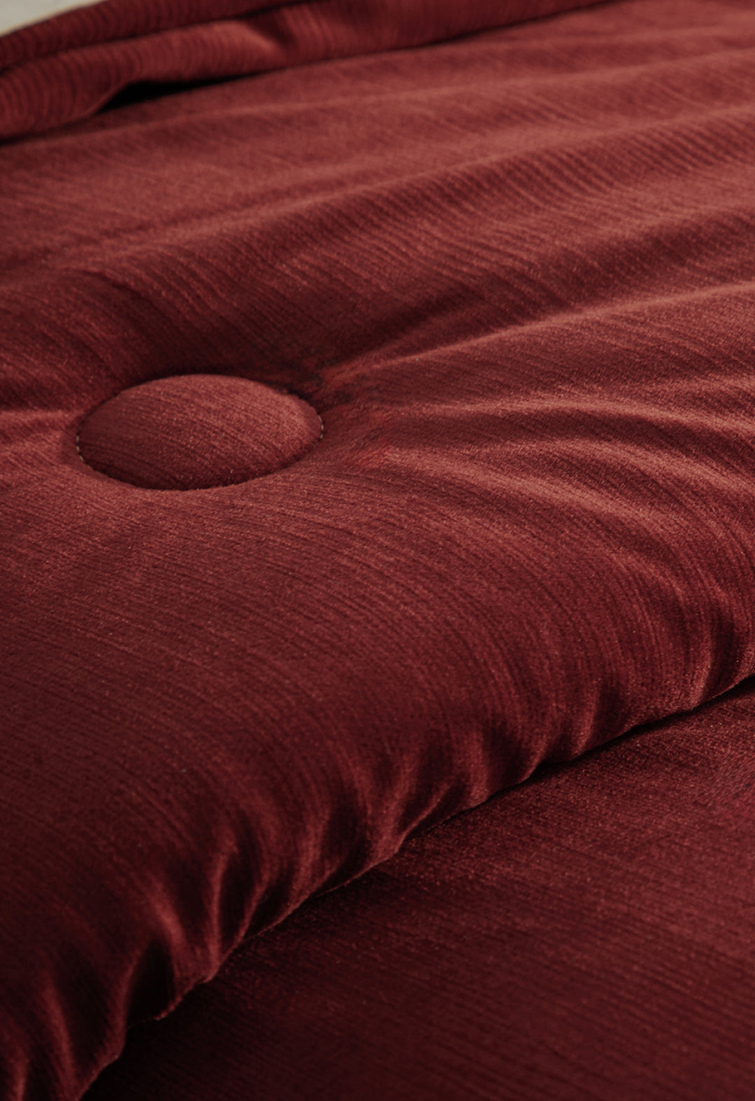 Close-up of the Edredón Súper Suave Janeiro by Intima Hogar, featuring soft rust-colored quilted microfiber with a raised button tuft and gentle folds, evoking the look of a plush, cushioned comforter.
