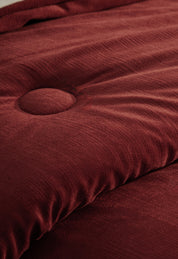 Close-up of the Edredón Súper Suave Janeiro by Intima Hogar, featuring soft rust-colored quilted microfiber with a raised button tuft and gentle folds, evoking the look of a plush, cushioned comforter.