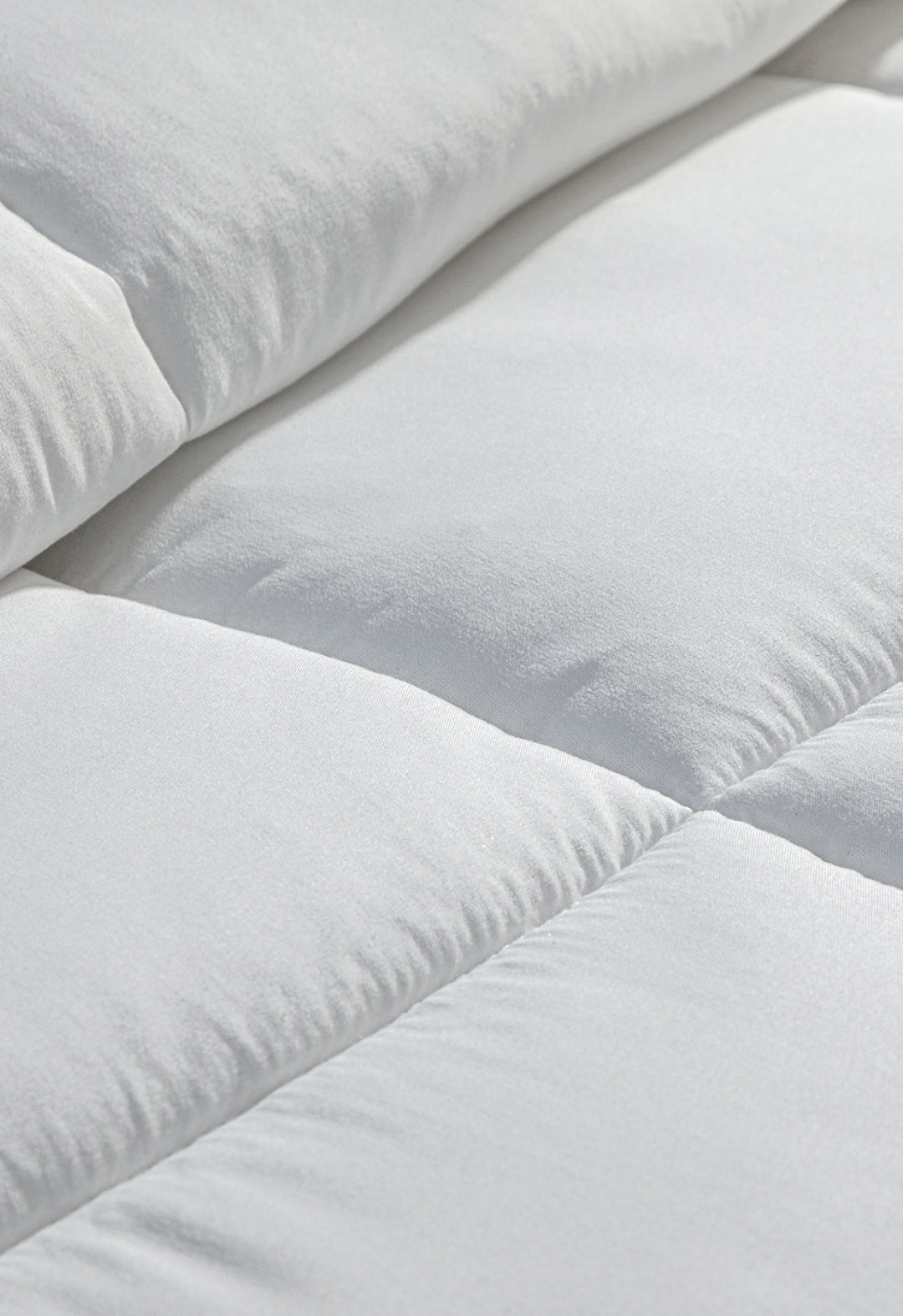 Close-up of the white, quilted surface of the Edredón Súper Suave Maxiplus by Intima Hogar, highlighting its soft texture and stitching—perfect for calidez envolvente y un descanso reparador.
