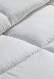 Close-up of the white, quilted surface of the Edredón Súper Suave Maxiplus by Intima Hogar, highlighting its soft texture and stitching—perfect for calidez envolvente y un descanso reparador.