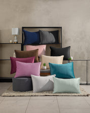The Funda de Almohada Ensueño Vino by Intima Hogar adds a stylish touch to any modern room with its elegant color, complementing decor like lamps and plants on chairs, ottomans, or shelves against a neutral backdrop.