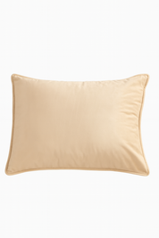 La Funda de Almohada Ensueño Beige de Intima Hogar presenta un diseño rectangular en tono claro, superficie suave y ribete elevado, ideal para aportar elegancia a cualquier habitación. Se muestra sobre fondo blanco.