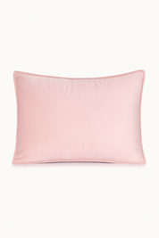 La Funda de Almohada Ensueño Rosa de Intima Hogar, rectangular y de suave textura, en tono rosa claro con ribete rosado más oscuro, es ideal para el descanso en cualquier habitación. Se muestra sobre fondo blanco.
