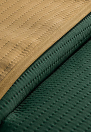 Close-up of the Juego de Edredón Ligero Honor by Intima Hogar, featuring double-sided textured fabrics in mustard yellow and dark green with evenly spaced stitched lines.