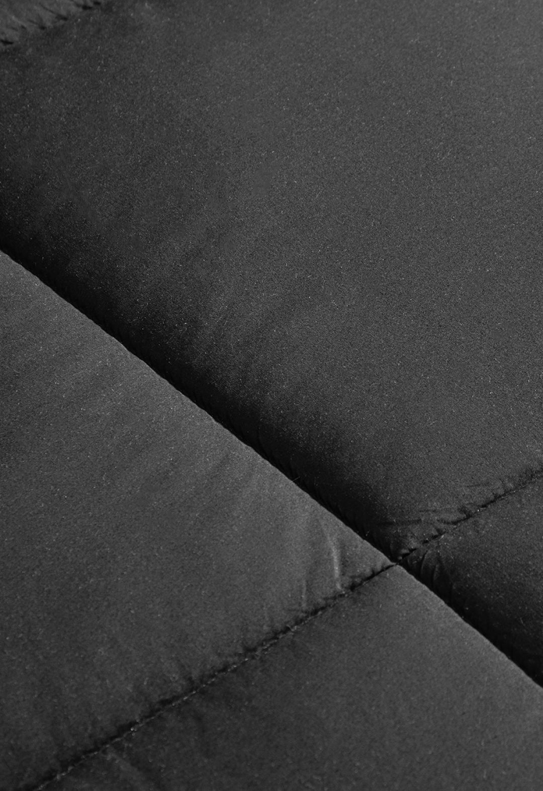 Close-up of black quilted fabric with visible stitching and a matte texture, perfect for the Juego de Edredón Marco de Intima Hogar, un edredón de microfibra con calidez ligera y diseño moderno.