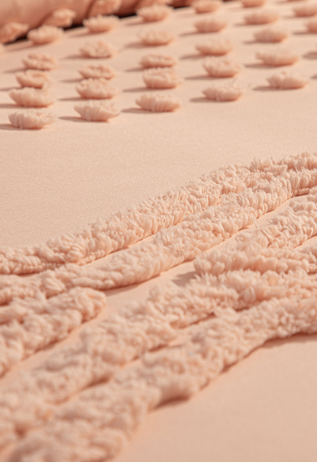 Close-up of the Juego de Edredón Sedona by Intima Hogar in soft peach, featuring raised textured patterns with fluffy dots and wavy lines for a cozy, tactile feel—perfect for winter warmth.
