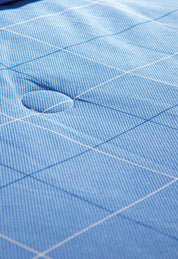 Close-up of the Juego de Edredón Royal Cotton Eleganza by Intima Hogar in blue with a white grid pattern, featuring a circular indentation and visible stitching for a diseño clásico.