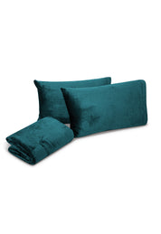 Three teal velvet pillowcases and a matching folded bedsheet from the Juego de Sábanas Invernales Azul Petróleo by Intima Hogar are displayed on a white background.