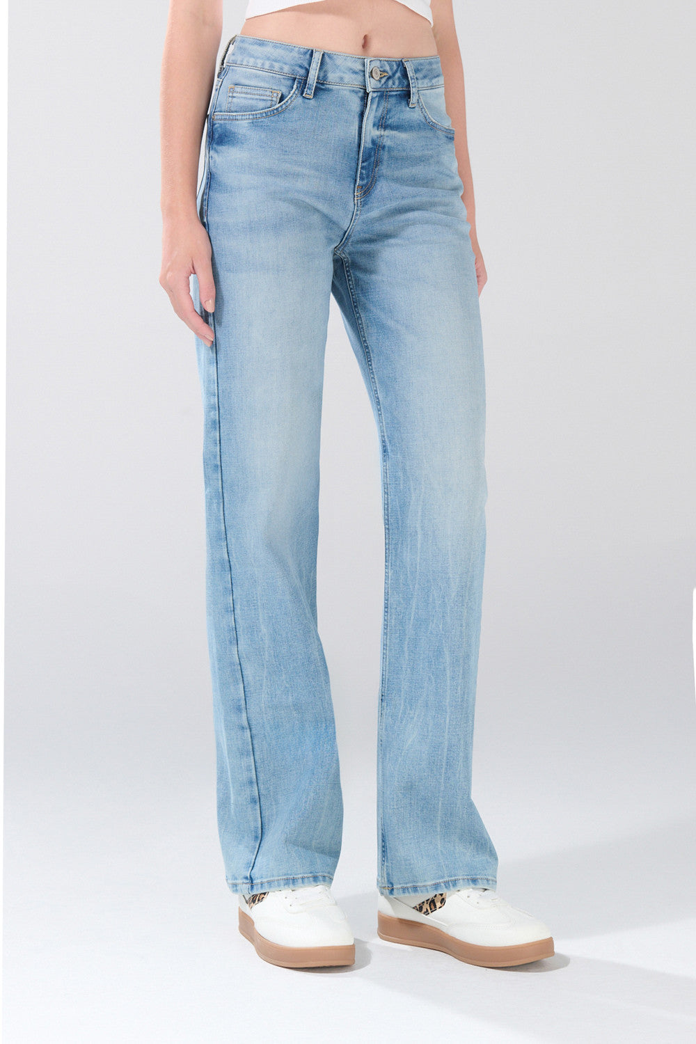 A person is shown wearing KOAJ PANTALON KOAJ JEAN STRAIGHT LEG 31397 1/, a light blue, high-waisted straight leg jean from KOAJ, paired with white sneakers. The image features only the lower torso and legs against a plain light gray background.