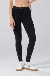 A woman wears KOAJ PANTALON KOAJ JEAN PUSH UP 32008 1/26, high-waisted black skinny jeans by KOAJ, paired with white sneakers featuring leopard print details. The photo is cropped from the waist down against a light gray background.