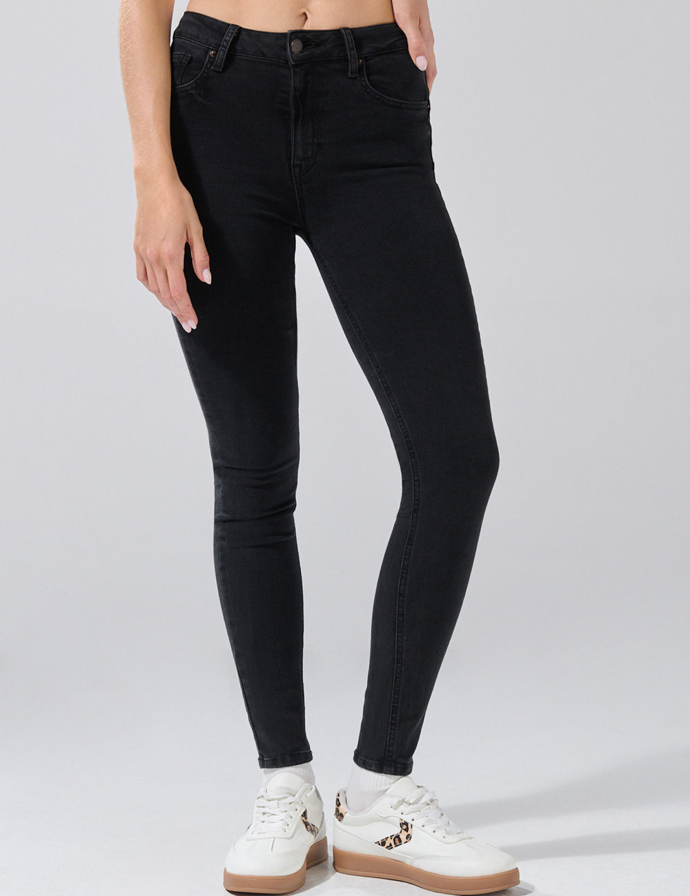 26, paired with black and white sneakers featuring leopard-print accents. Only their lower torso, legs, and feet are visible against a plain light gray background.