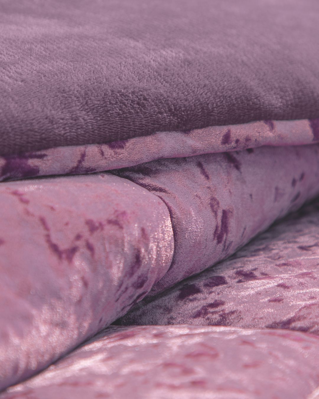 Close-up of the Cobertor Velvet Ice Deluxe Amatista by Intima Hogar, featuring soft, folded pink and purple velvet fabric with a plush, textured surface and a slight sheen.