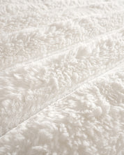 Close-up of the Cobertor Platinum Extra Suave Antártida by Intima Hogar, featuring soft, fluffy white faux fur with a wavy textured pattern and diagonal lines, giving it a cozy and plush appearance.