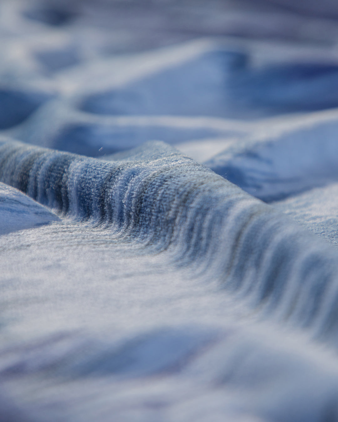 Close-up of the Cobertor Flannel Ligero Miami by Intima Hogar, featuring soft blue fabric with gentle, wavy folds and a textured surface for an abstract and tranquil look.