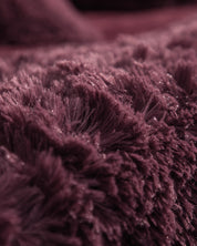 Close-up of the Cobertor Platinum Extra Suave Nevada by Intima Hogar: its rich, dark burgundy fabric features a deep pile texture with delicate, sparkling highlights, offering an ultra-soft feel and inviting warmth—perfect as a cozy, luxurious cobertura acogedora for your home.