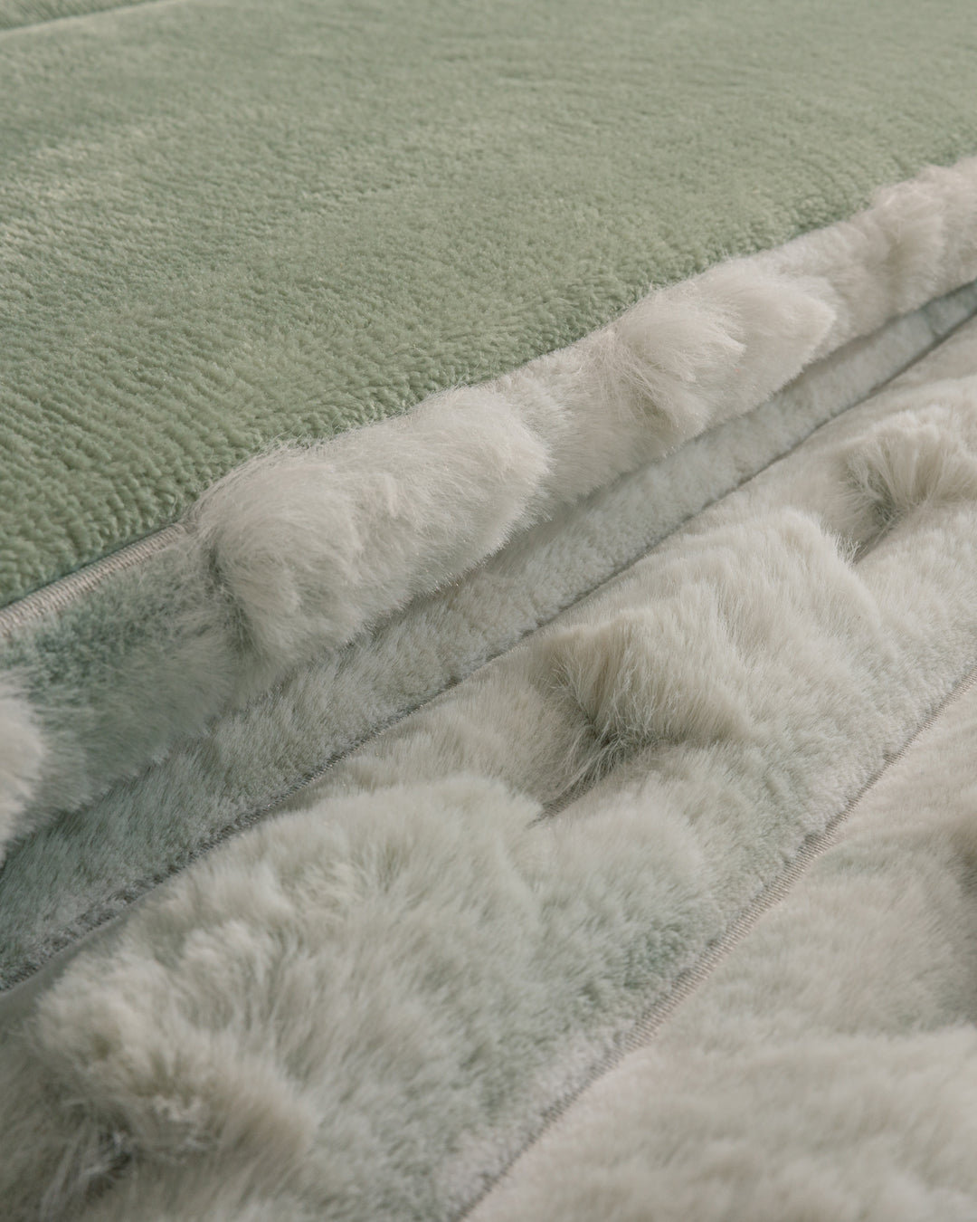 Close-up of the Cobertor Platinum Extra Suave Siberia by Intima Hogar, displaying its pastel green and white faux fur fabric, soft and fluffy texture, and subtle color variations.