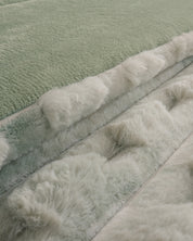 Close-up of the Cobertor Platinum Extra Suave Siberia by Intima Hogar, displaying its pastel green and white faux fur fabric, soft and fluffy texture, and subtle color variations.