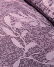Close-up of the Edredón Súper Suave Maya by Intima Hogar, featuring purple fabric with a subtle textured pattern and a light floral or leafy design woven into the super soft material.