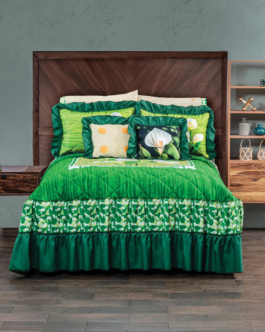 A neatly made bed features Intima Hogar's Juego de Colcha Doble Olán Cala, with green calla lily and leaf prints, matching pillows, a wooden headboard, built-in nightstand, and wood floor.