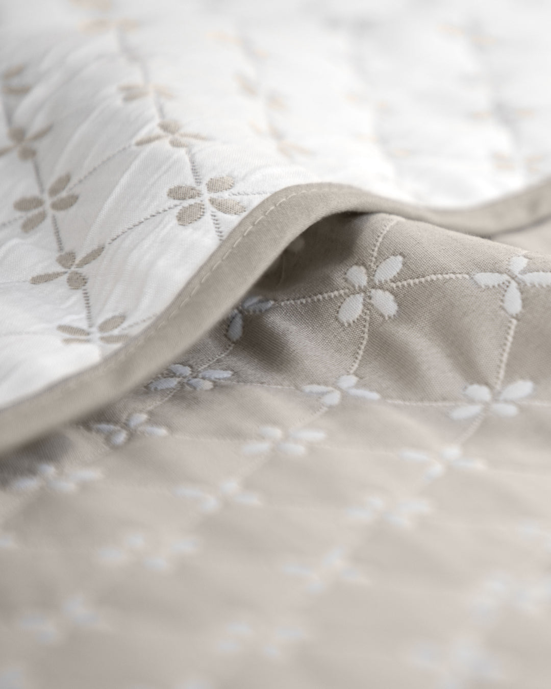 Close-up of the Juego de Edrecolcha Doble Vista Laurel by Intima Hogar, featuring soft quilted fabric with a subtle floral pattern in light beige and white tones; detailed stitching and texture make it perfect for an elegant colcha King or reversible colcha doble vista.